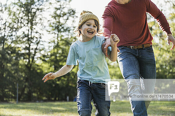 Playful father running with son in park