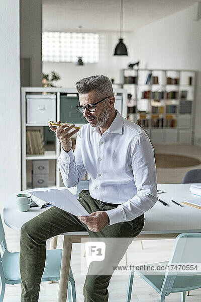 Mature businessman talking on mobile phone in office