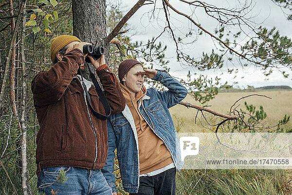 Father and son bird watching in forest