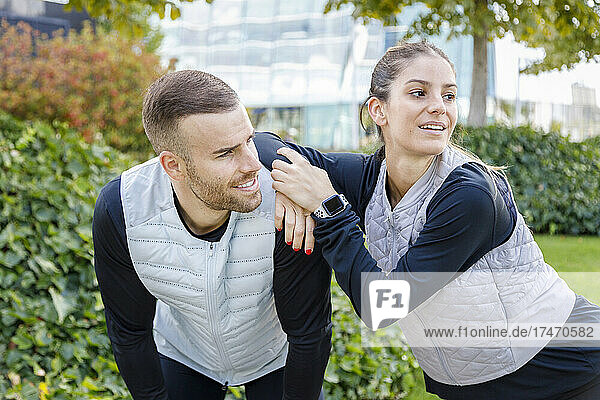 Female athlete leaning on male friend at park