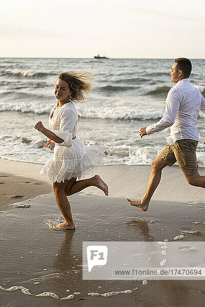 Girlfriend and boyfriend running at beach by sea