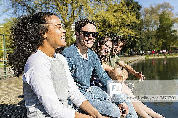 Lachende Frau mit Freunden an sonnigem Tag im Park