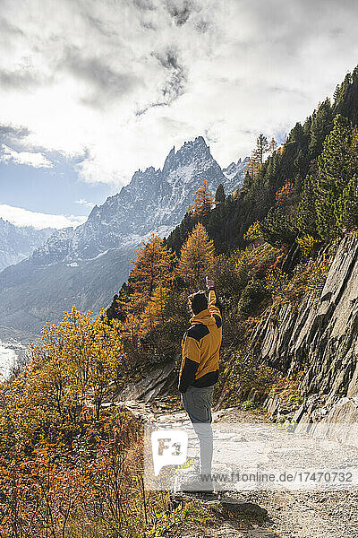 Young man standing in front of Aiguille des Grands Charmoz on sunny day  Chamonix  France