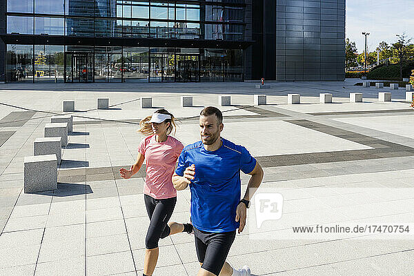 Junger Sportler läuft mit Frau auf Fußweg