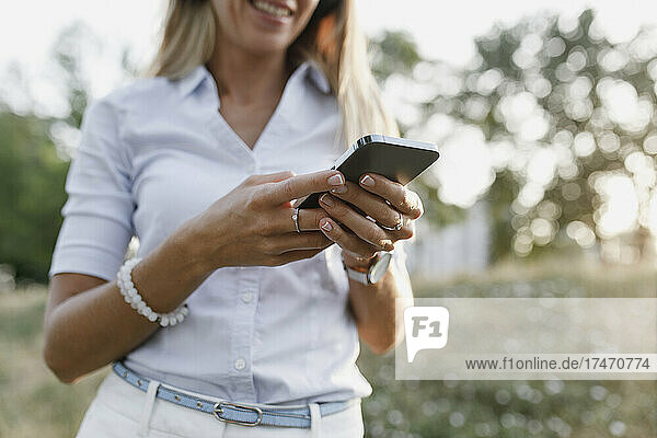 Frau in weißer Freizeitkleidung benutzt Smartphone