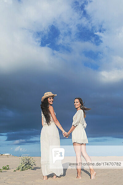 Smiling lesbian couple holding hands on beach
