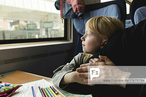 Girl looking out of window by father in train
