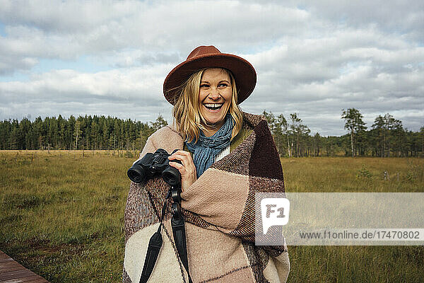 Laughing woman with blanket holding binoculars