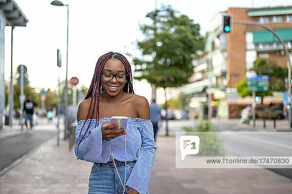 Lächelnde Frau benutzt Mobiltelefon auf Fußweg
