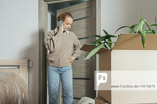 Frau telefoniert in neuer Wohnung mit Smartphone