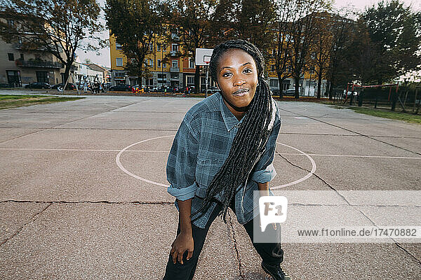 Smiling woman with locs hairstyle standing at basketball court