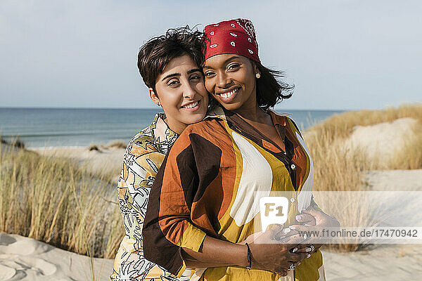 Affectionate lesbian couple embracing at beach on sunny day