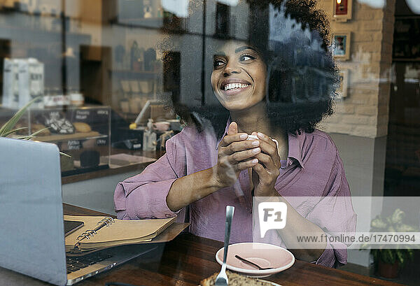 Smiling freelancer with coffee cup looking out of window