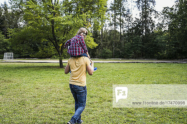 Playful man carrying boy on shoulders in park