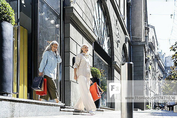 Frauen gehen mit Einkaufstüten in der Hand vor den Laden