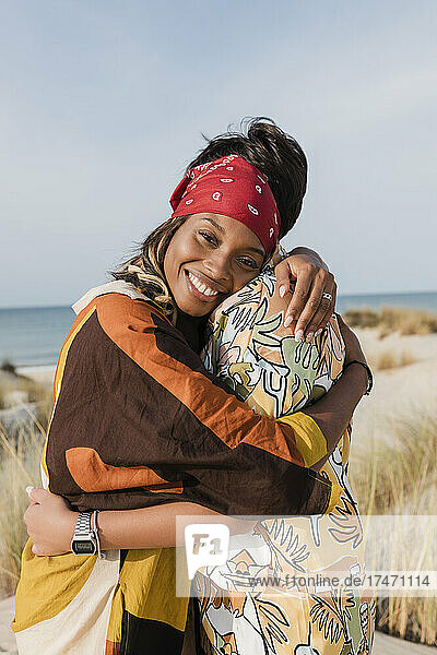 Glückliche Frau umarmt lesbische Freundin am Strand