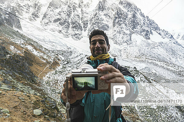 Smiling man taking selfie through camera in front of snowcapped mountain  Chamonix  France