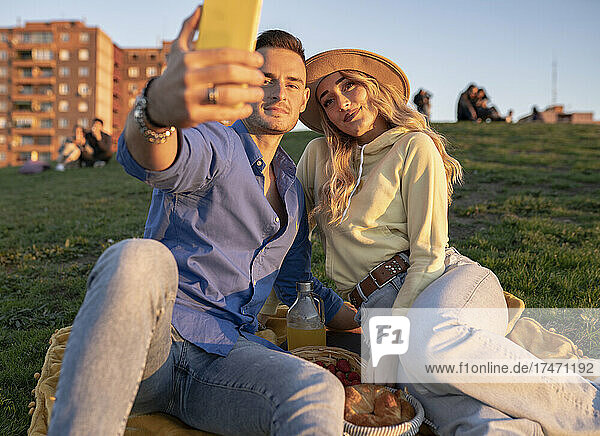 Boyfriend taking selfie with girlfriend through smart phone on hill