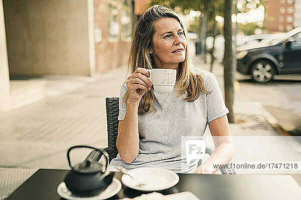 Reife Frau denkt nach  während sie im Straßencafé Tee trinkt