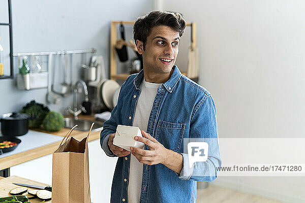 Young man holding box in kitchen
