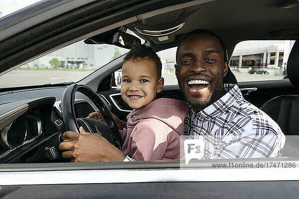 Cheerful father and son playing in car