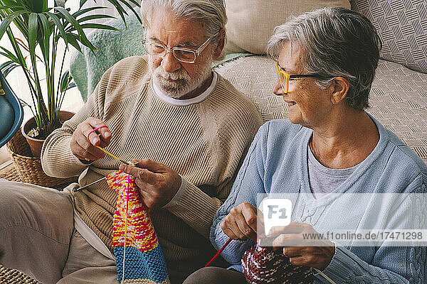 Couple knitting wool in living room
