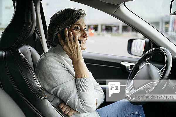 Woman talking on smart phone while sitting in car