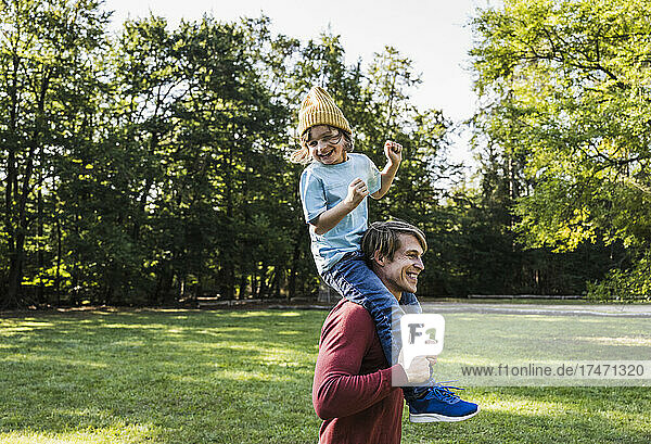 Playful man carrying boy on shoulders in park