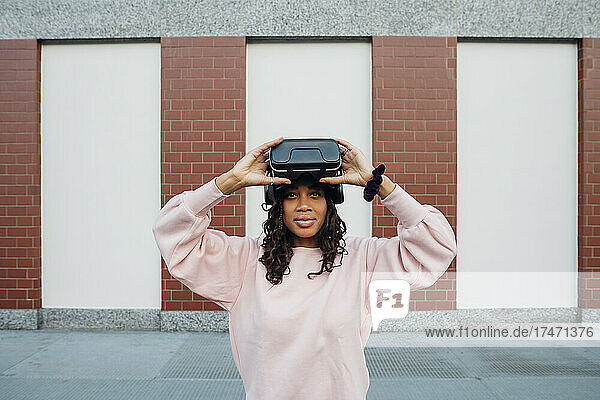 Woman holding virtual reality headset on footpath