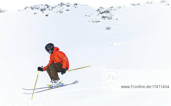 Man in red jacket skiing on snowcapped mountain