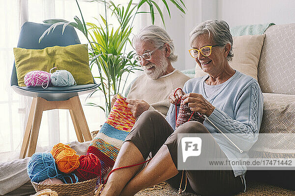 Älteres Paar strickt Wolle im Wohnzimmer