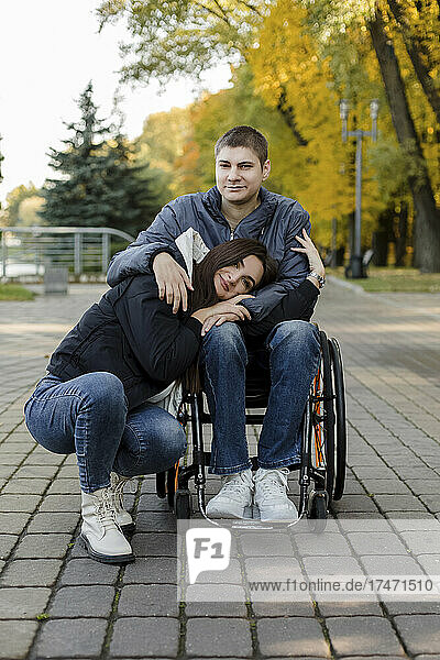 Young girlfriend leaning on disabled boyfriend's lap at park
