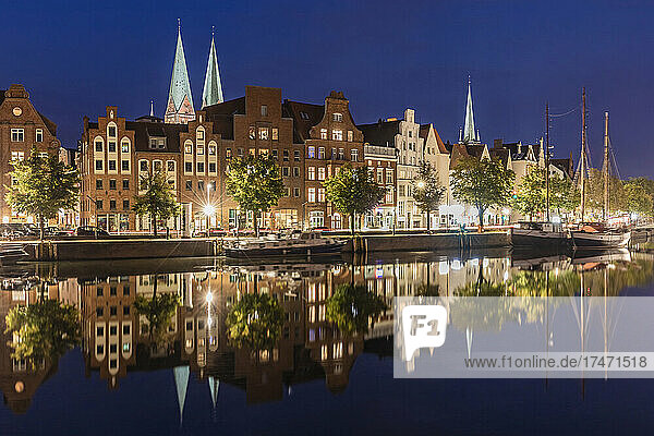 Germany  Schleswig-Holstein  Lubeck  Long exposure of illuminated townhouses reflecting in river Trave canal at night