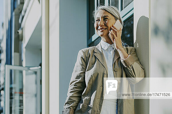 Woman smiling while talking on smart phone outside coffee shop