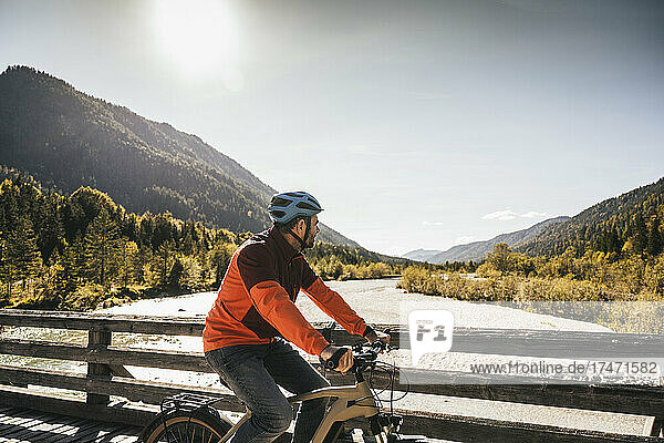 Man wearing helmet cycling on bridge
