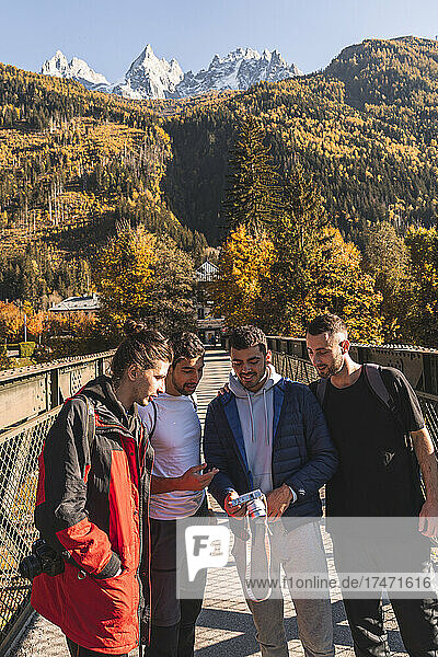 Man sharing digital camera with friends on footbridge  Chamonix  France