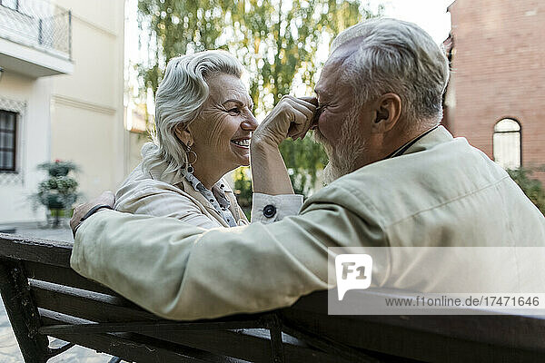 Senior woman playing with man nose on bench