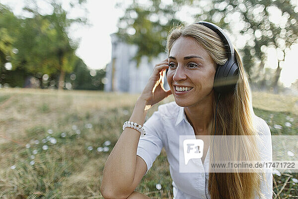 Blond woman listening music on wireless headphones