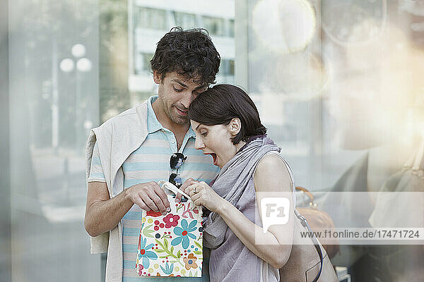 Couple peeking in gift bag during shopping