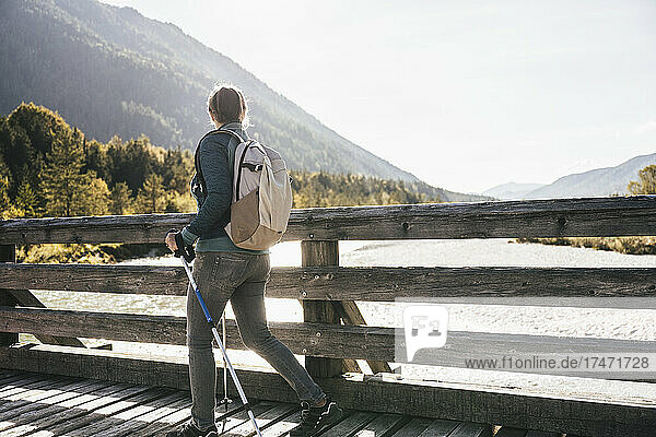 Female hiker with backpack walking on bridge