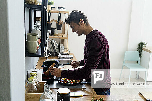 Happy man preparing food in kitchen