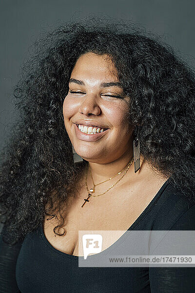 Happy woman with eyes closed against gray background