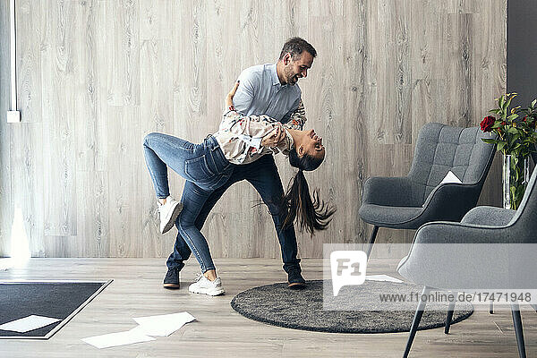 Smiling business couple dancing in office