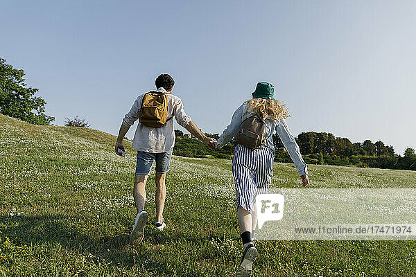 Couple with backpacks running on meadow