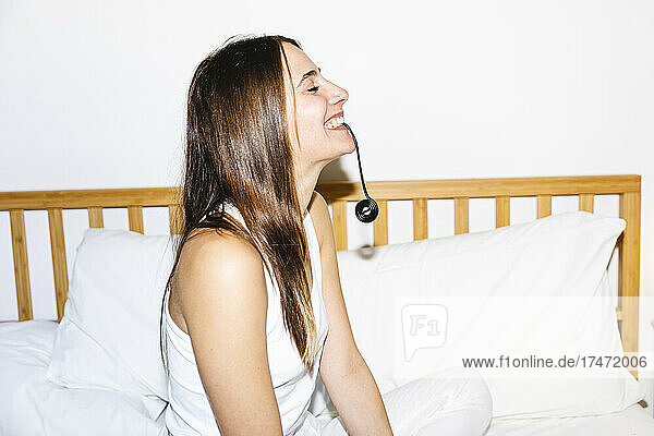 Glückliche junge Frau  die im Schlafzimmer Lakritzbonbons isst