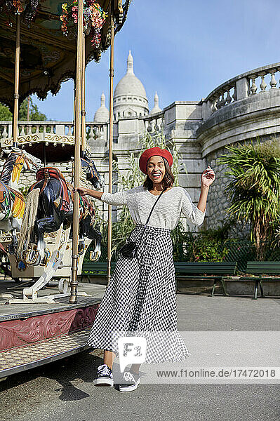 Playful woman at carousel with Basilique Du Sacre Coeur in background