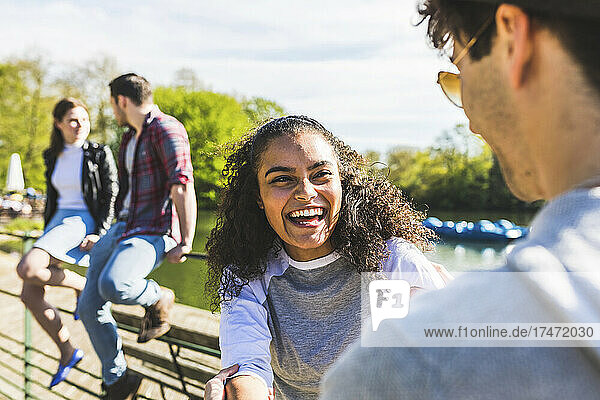 Lachende Frau blickt Mann an sonnigem Tag im Park an