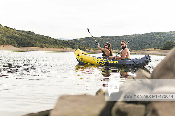 Male and female friends rowing in lake during vacation
