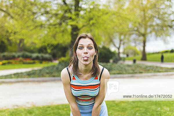 Verspielte Frau streckt im öffentlichen Park die Zunge heraus