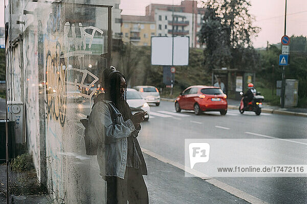 Junge Frau benutzt Mobiltelefon  gesehen durch Glas